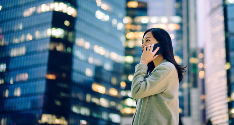 Young girl making a mobile phone call with the city as a backdrop